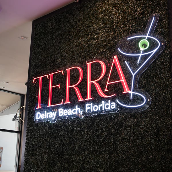 Terra Ristorante & Bar neon sign with a martini glass on a dark green textured wall.