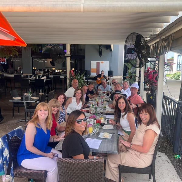 A large group of smiling people enjoying a meal and live music on the outdoor patio of Terra Ristorante & Bar.