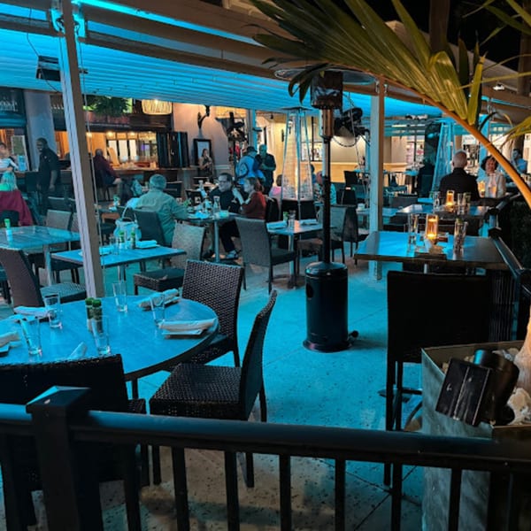 Diners seated at tables on an outdoor patio at Terra Ristorante & Bar, illuminated by blue lights.